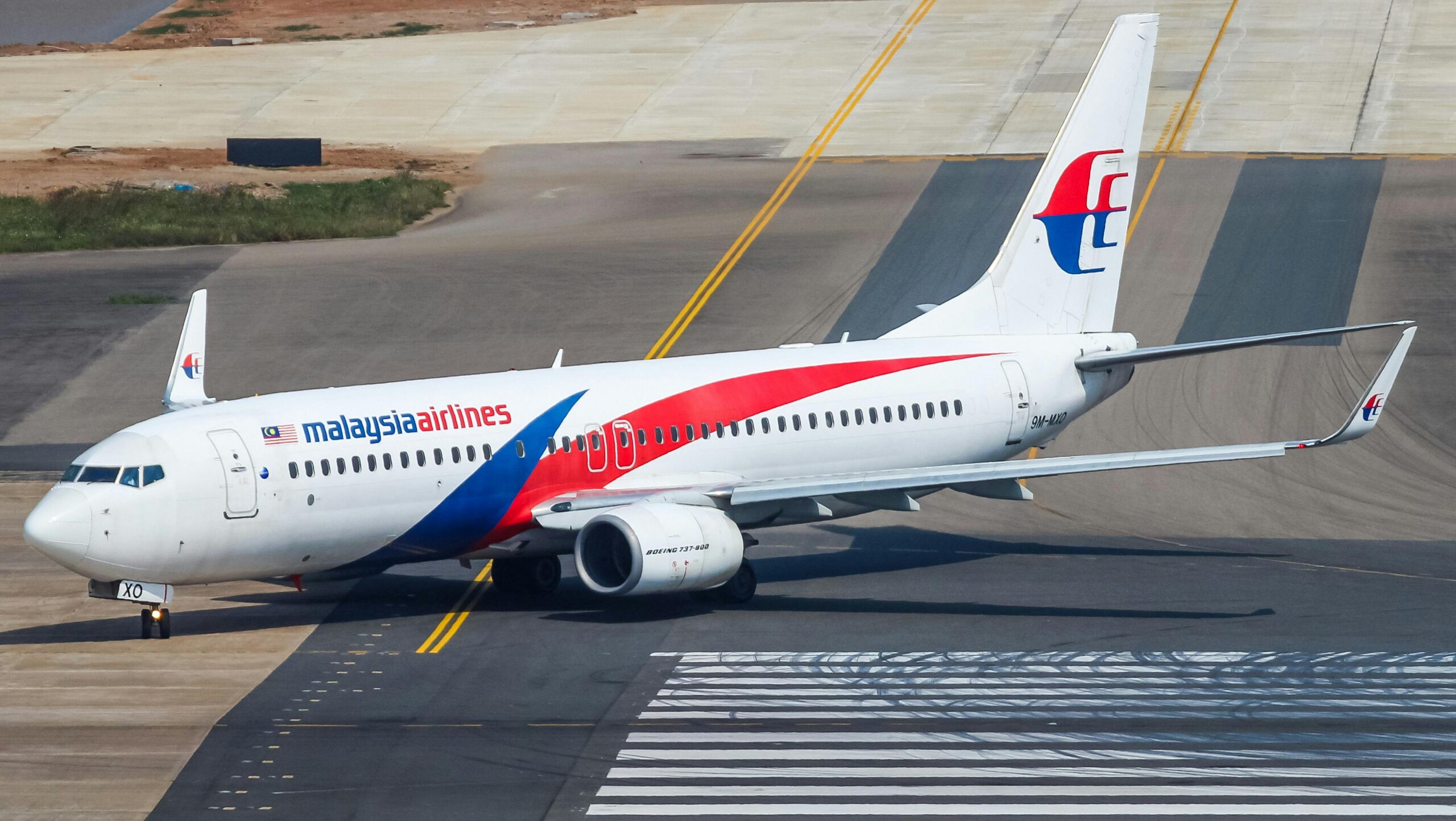 A Malaysia Airlines airplane taxiing on runway.